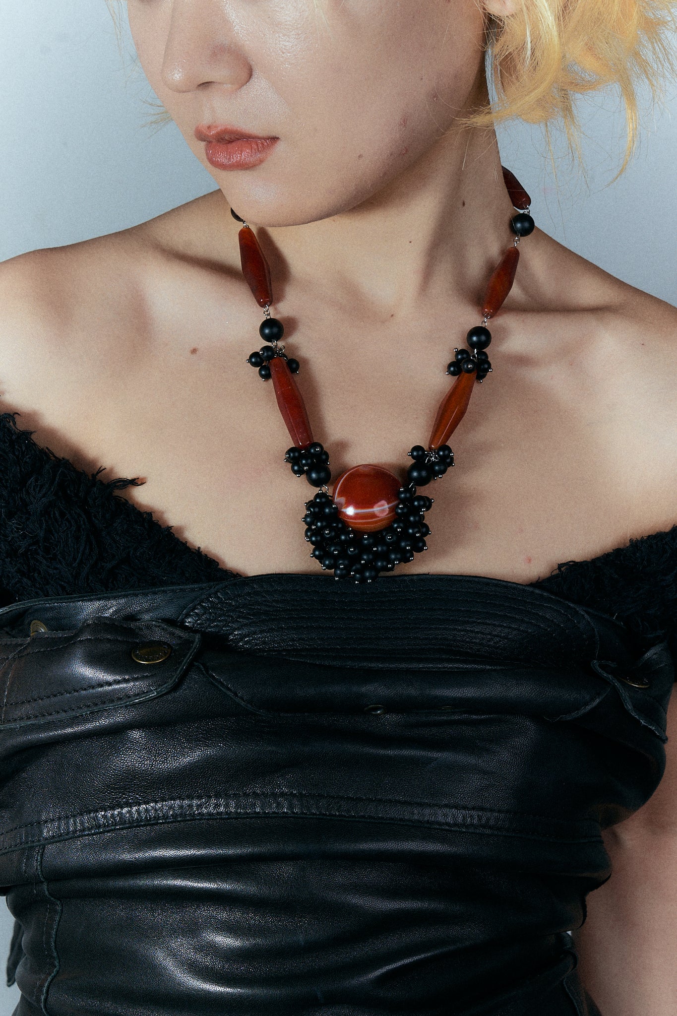 Person wearing a black and red beaded necklace against a neutral background